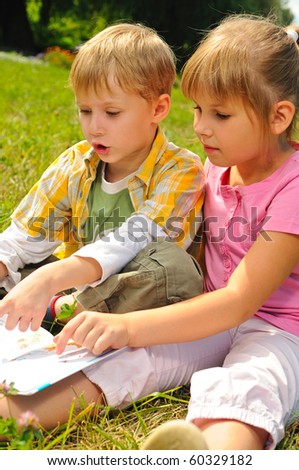 Boy and girl are reading a book outdoor