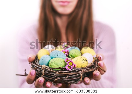 Woman hands holding painted easter egg in a small nest. Toned picture. Selective focus.