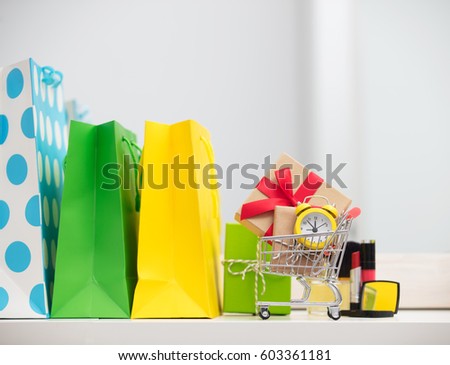 cute shopping bags, make up set, gifts and alarm clock in shopping cart on the wonderful mirror background
