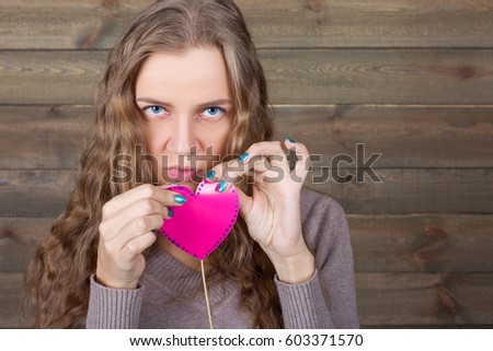 Young female with funny pink heart on a stick