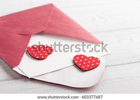 Red envelope with empty paper and red hearts on white table