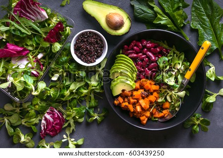 Quinoa salad in bowl with avocado, sweet potato, beans, herbs, spinat on concrete rustic background. Quinoa superfood concept. Clean healthy detox eating. Vegan/vegetarian food. Making healthy salad Royalty-Free Stock Photo #603439250