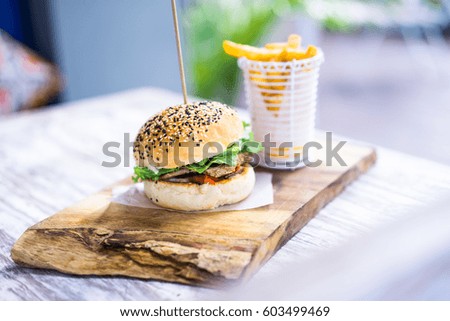 Delicious burger with fish and juicy greens, bun with sesame and french fries
