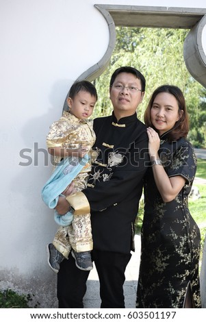 middle aged of Chinese family in Chinese black outfit at the park in summer 
