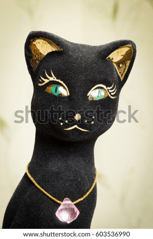 A statuette of a black cat with a jewel on the neck.