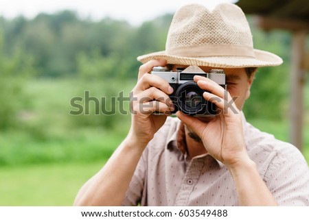 Young, handsome hipster taking pictures outdoors. Holiday, journey, vacation concept.