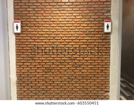 toilet sign with brick wall