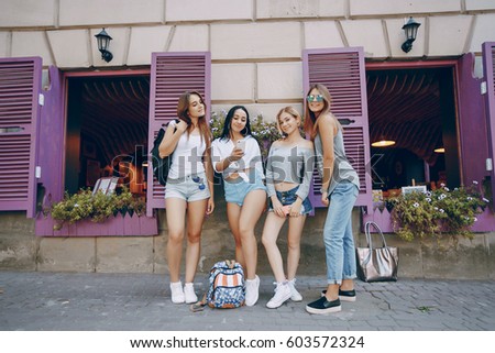 Four beautiful girls in stylish clothes in summer city