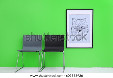 Modern chairs near green wall with abstract painting