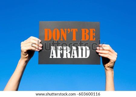 Black card placard with the concept of Don't Be Afraid against a clear blue sky background