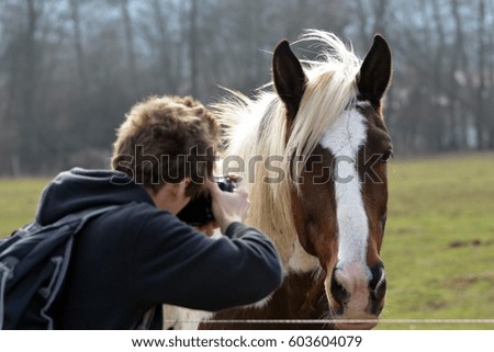 Young man photographing horses.