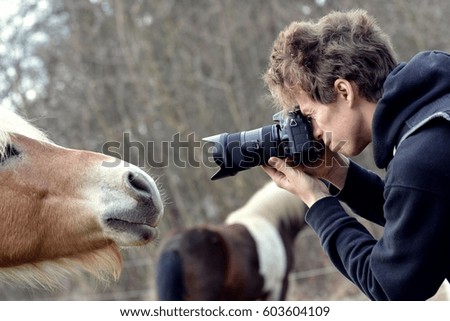 Young man photographing horses.
