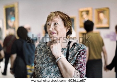 Closeup on attentive positive senior woman visiting museum and enjoying arts