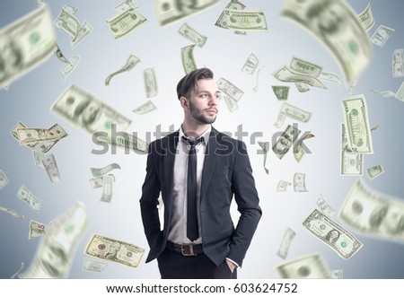 Portrait of a bearded businessman standing with his hands in the pockets near a gray wall under a dollar rain