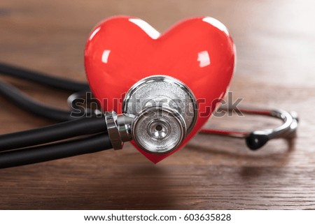 Close-up Of A Red Heart With Stethoscope On Wooden Desk