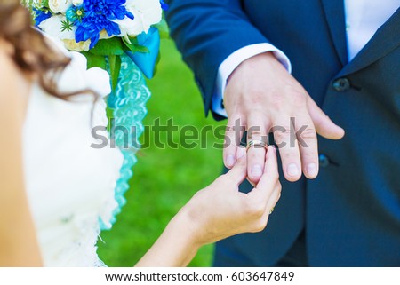 The bride places the wedding ring on the groom's finger. The ceremony of marriage  in nature. Hand closeup.
