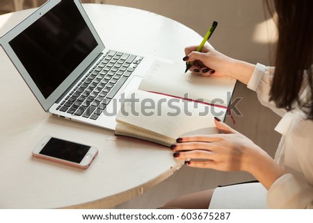 a right hand writing on paper which is on wooden table