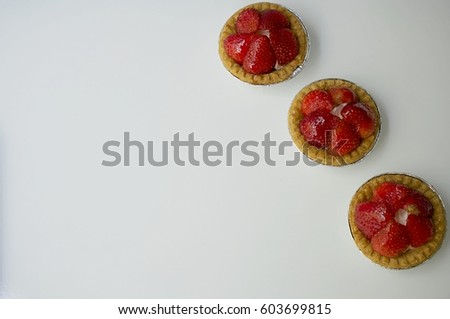 Sweet strawberry cakes on white background against gray wall. Full frame image. Flat lay view. Picture with copyspace.