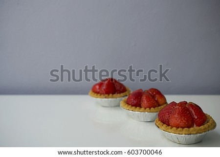 Sweet strawberry tartes on white background against grey wall. Full frame image. Horizontal picture with copyspace.