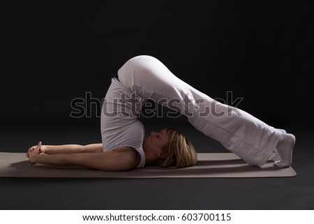 Woman exercising yoga indoors on black background,Yoga --Plow pose/Halasana