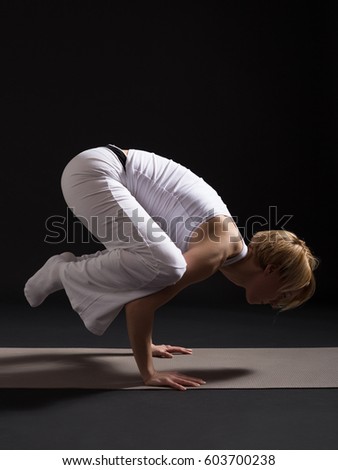 Woman exercising yoga indoors on black background,Yoga -Crane Pose/Bakasana