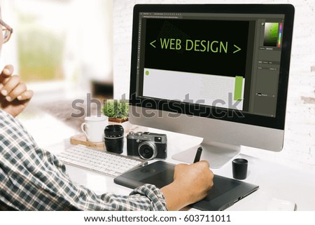 Graphic designer using digitizer or Graphic tablet at his desk designing web site in creative office.