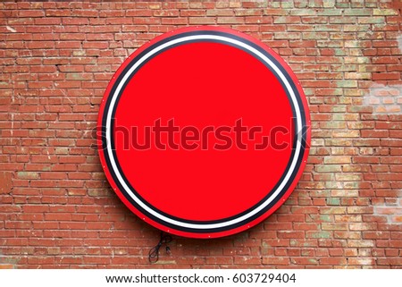 Round empty red banner hanging on a brick wall