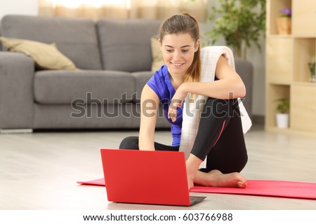 Fitness woman selecting tutorial before exercise sitting on the floor in the living room at home