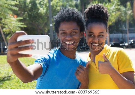 Young african american man with latin woman taking selfie with phone