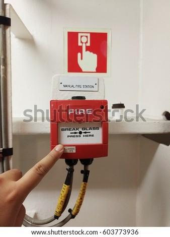 View of manual alarm call point for fire emergency with demonstration of finger pressing to activate alarm