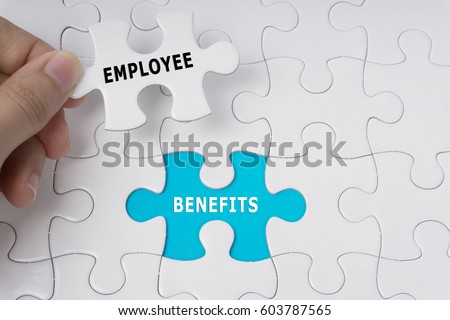 Hand holding piece of jigsaw puzzle with words Employee Benefits. Royalty-Free Stock Photo #603787565