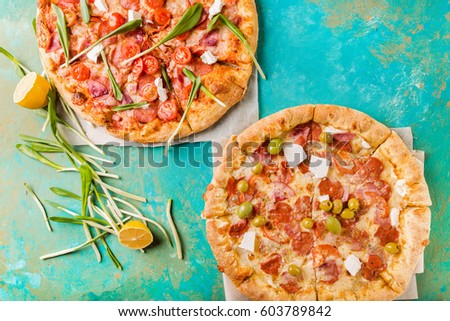 Spring pizzas with cherry tomatoes and ham on a turquoise abstract background. 