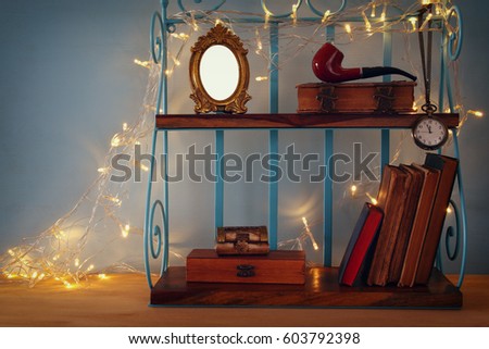 Classical shelf with vintage male objects and blank frame with gold garland lights. Ready to put photography