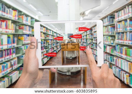 Augmented reality education concept. Hand holding digital tablet smart phone use AR application to check library category in bookshelf at university library. Royalty-Free Stock Photo #603835895