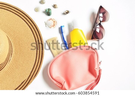 Flat lay photography the contents of a beautician for travel. Hat, comb, blue toothbrush, yellow bottle of sunscreen and brown sunglasses. Summer rest concept