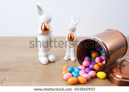 Two bunnies around eggs on wooden table. Easter time.