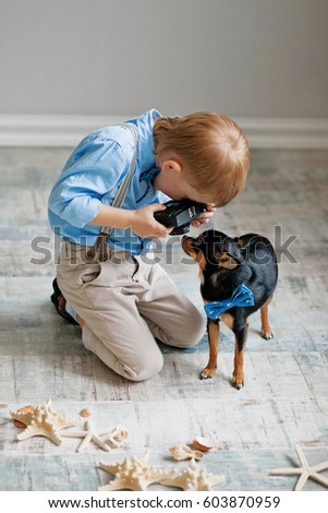 The boy takes pictures of the dog