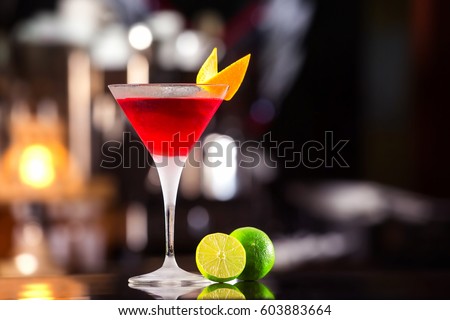 Closeup glass of cosmopolitan cocktail decorated with orange at bar background. Royalty-Free Stock Photo #603883664
