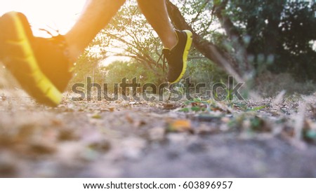 Athlete runner feet running on trail. Close up of trail running shoe. blurred sport background