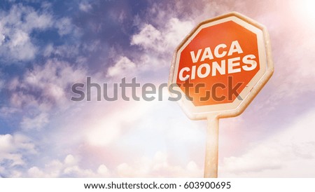 Vacaciones, Spanish text for Vacation, text on red traffic stop sign in front of cloudy blue sky with lens flares