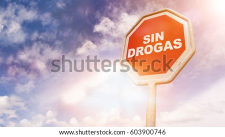 Sin drogas, Spanish text for No drugs, text on red traffic stop sign in front of cloudy blue sky with lens flares