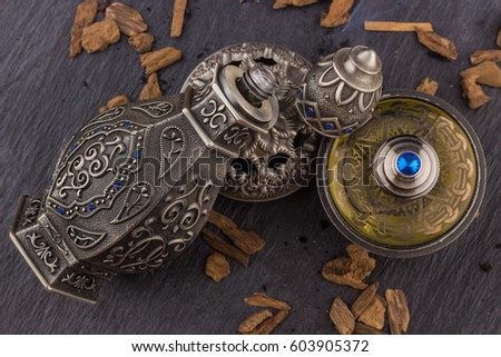 Silver Oriental Artisitc Arabian Oud Perfume / Arabian Oud Perfume with Oud Scented Wood burned in the background with Scented Smoke in the Air 