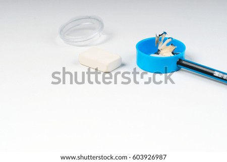 Pencil sharpener shavings and elastic on the white paper. Back to school.
