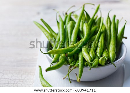 Green beans in white bowl on cutting board. Royalty-Free Stock Photo #603941711
