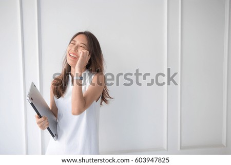 Beautiful Asian woman smiling while talking in the phone in simple white dress. Simple white background. Copy space. Dating, business or friendship concept. 