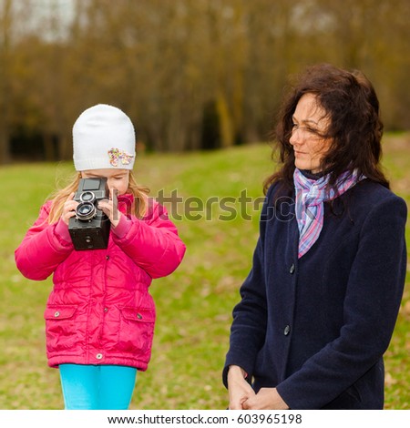 Mom and daughter are photographed on a retro camera. The concept of hobby photography.