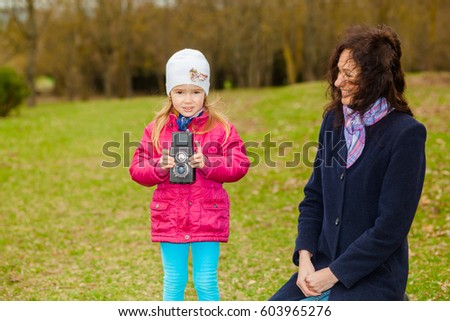 Mom and daughter are photographed on a retro camera. The concept of hobby photography.