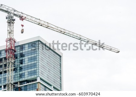 Building under construction with glass facade with construction crane Royalty-Free Stock Photo #603970424