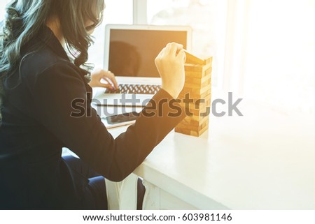 Planning, risk and strategy in business, business woman gambling placing wooden block on a tower