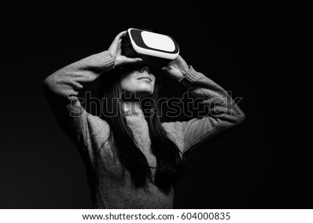 Studio portrait of pretty young female using new virtual reality glasses for mobile vr game application.Girl use mobile games apps with innovative 3d vr headset.Trendy augmented reality gadget in use